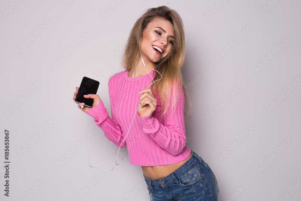 Naklejka premium Attractive young woman relax and dance on gray background . Portrait of happy girl listening to music in headphones and dancing