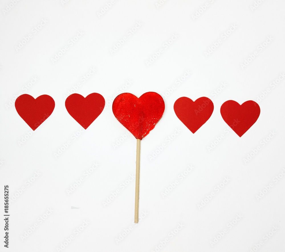 a series of five hearts, among them a candy in the shape of a heart on a stick.