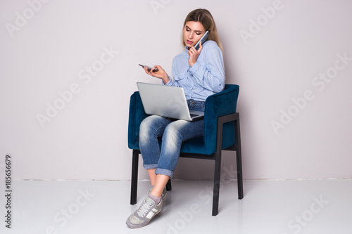 Overwhelmed business woman sitting at her chair. Too many calls in one day. Two phones and laptop.