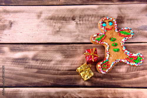 Ginger biscuit in the form of a man with two gift boxes on a natural dark wooden background.