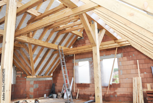 Unfinished House Attic Construction Interior. Building house attic room with roofing wood trusses, frame, wooden beams.
