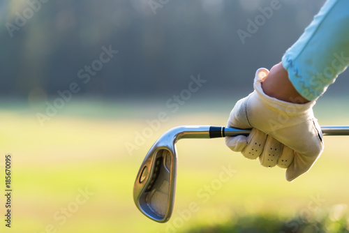 Close up of a female golfer holding an iron behind his body