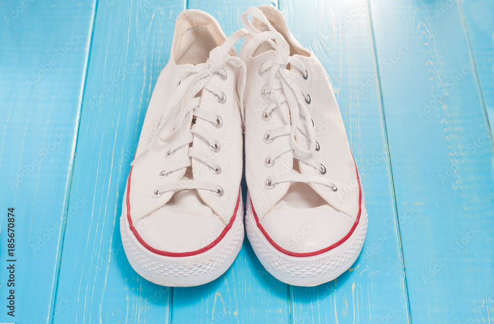 A pair of new white hipster sneakers on a wooden background