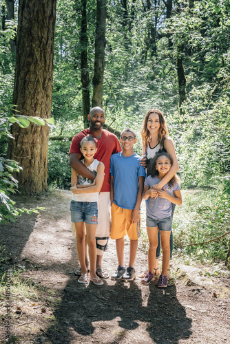 Portrait of happy mixed race family standing in forest
