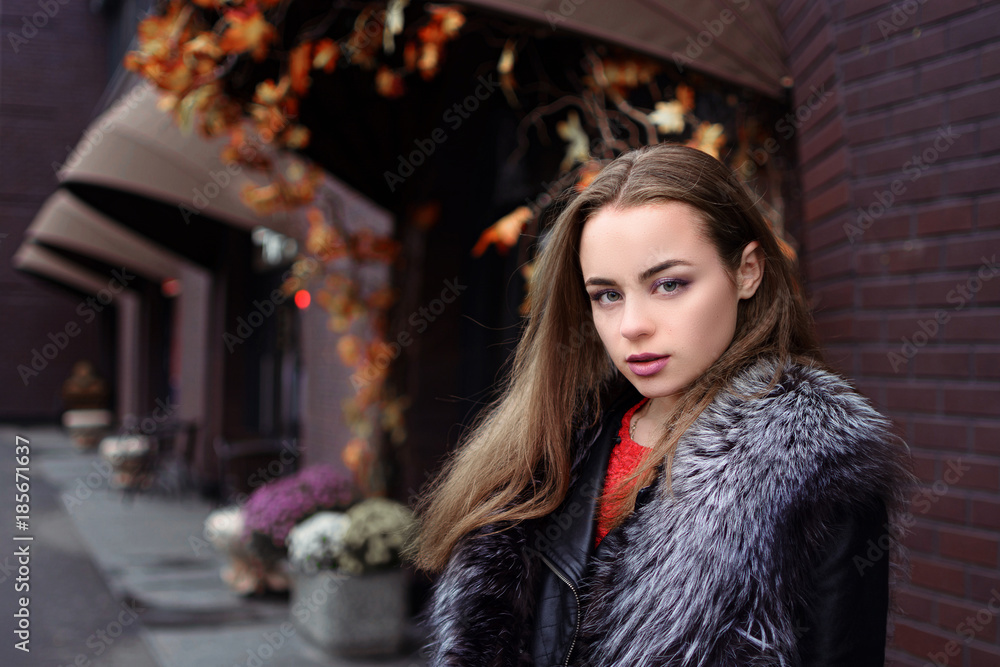 beautiful young girl with a smile in a fur vest on the street in autumn beautiful young girl with a smile in a fur vest on the street in autumn