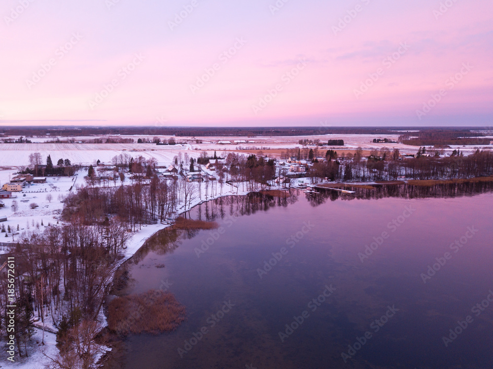 Beautiful colorful sunrise over a half frozen lake during winter. Tartu, Estonia.