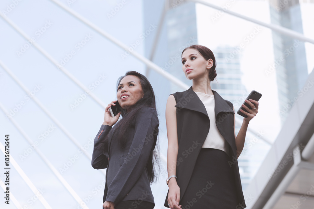 Two beautiful confident business woman talking on phone together. Two beautiful confident business woman talking on phone together.