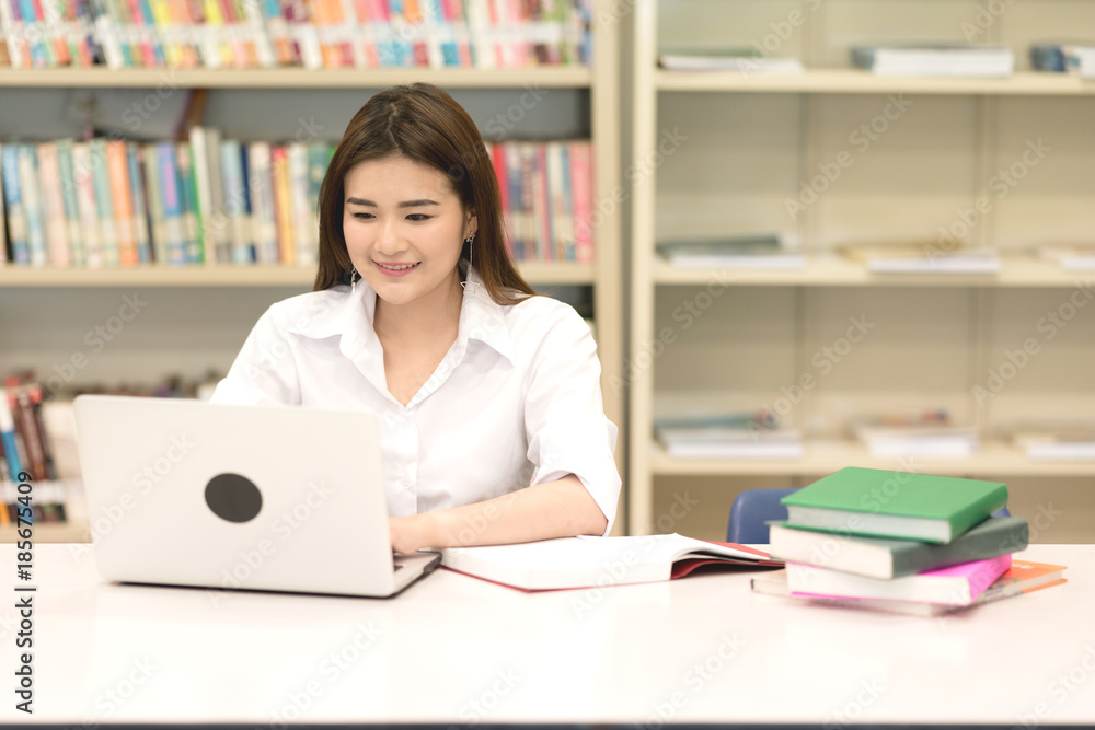 Young student study hard in library. Asian female university student doing study research in library with laptop on desk and smiling. For back to school education diversity concept. Young student study hard in library. Asian female university student doing study research in library with laptop on desk and smiling. For back to school education diversity concept.
