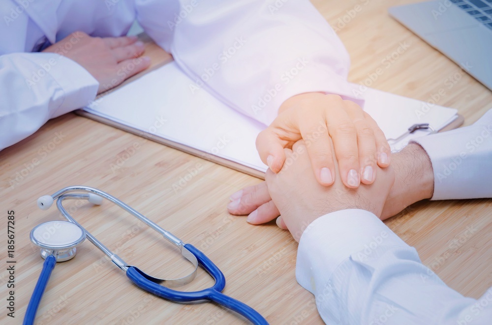 kind and friendly young female doctor hand reassuring and giving real support for male patient with laptop, clipboard and stethoscope on desk in hospital, medical, age, health and carefully concept kind and friendly young female doctor hand reassuring and giving real support for male patient with laptop, clipboard and stethoscope on desk in hospital, medical, age, health and carefully concept