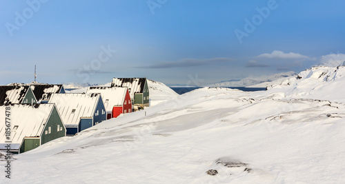 Green, blue, red and green inuit houses covered in snow at the fjord of Nuuk city, Greenland