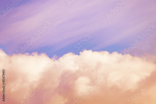 Orange fluffy clouds illuminated by the sunlight against a gently pink sky background (toned)