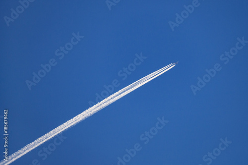 Airplane with an condensation trace behind in the deep blue sky