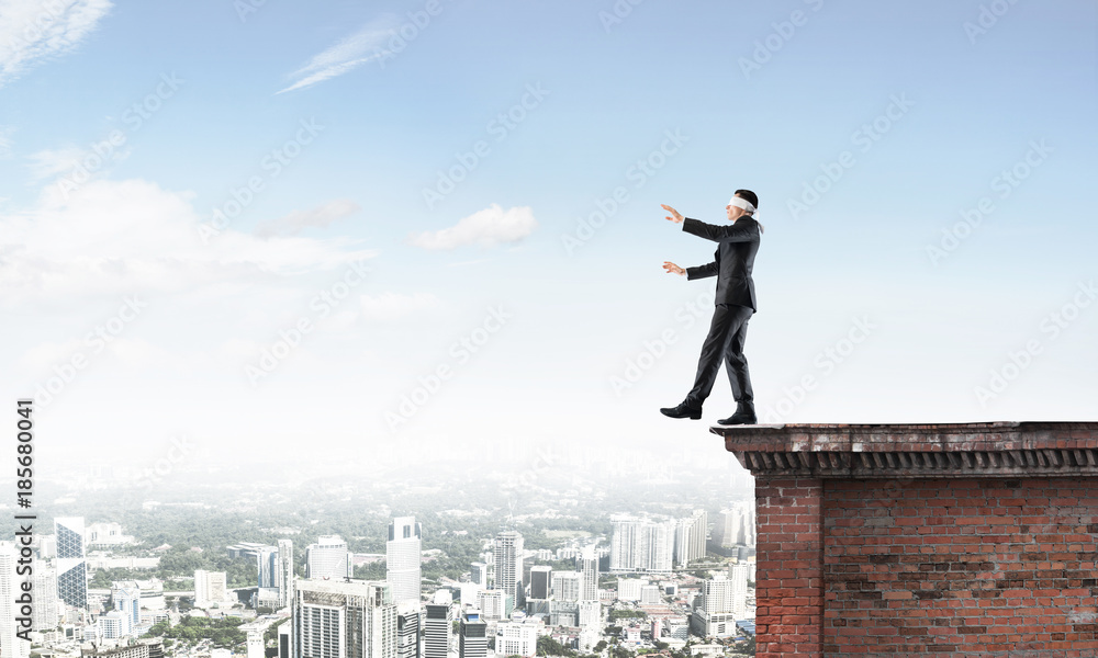 Danger and risk concept with businessman making step from edge Danger and risk concept with businessman making step from edge