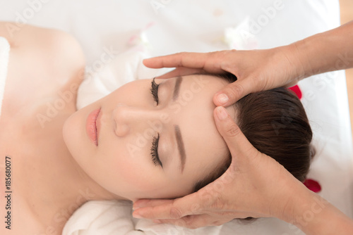 Asian exotic holiday spa concept. Beautiful young chinese woman enjoy relaxing during face massage at spa, taken indoor in real spa location. Top view.