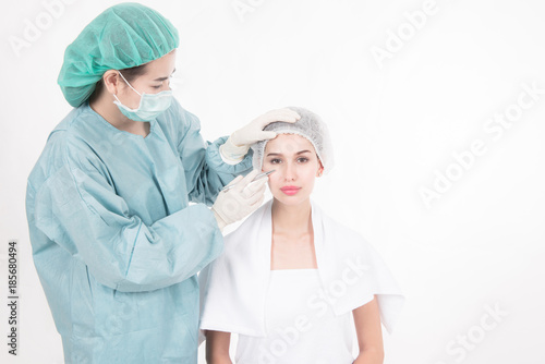 Professional plastic surgery services. Portrait of beautiful white woman face being study by female doctor to identify which area to enhance her face with surgery techniques. Isolated in white.