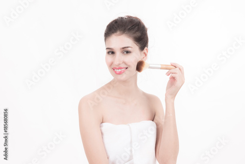 Woman beauty concept. Beautiful white woman wrapped in white towel isolated in white holding a make up brush. Beauty concept.