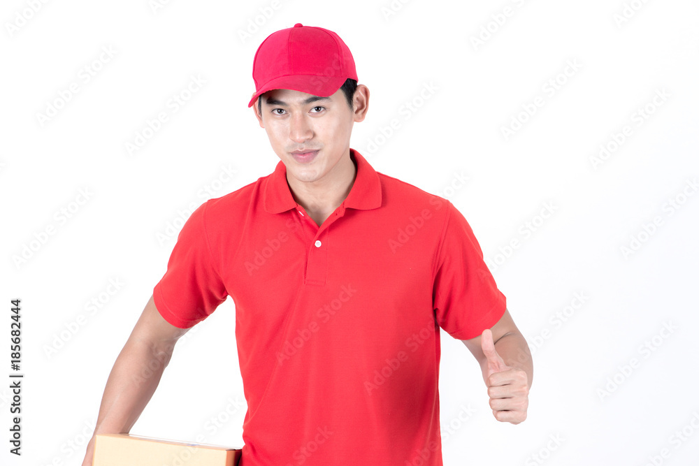 Young logistic career concept. Happy delivery man with box and thumbs up. Isolated on white background. Asian chinese fit man in red polo shirt and jeans with red hat in his early twenties.