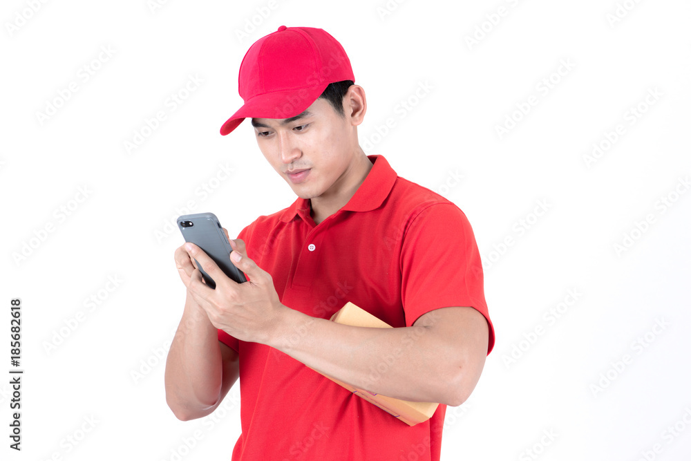 Young logistic career concept. Happy delivery looking for customer address on his phone. Isolated on white background. Asian chinese fit man in red shirt and jeans with red hat in his early twenties. Young logistic career concept. Happy delivery looking for customer address on his phone. Isolated on white background. Asian chinese fit man in red shirt and jeans with red hat in his early twenties.