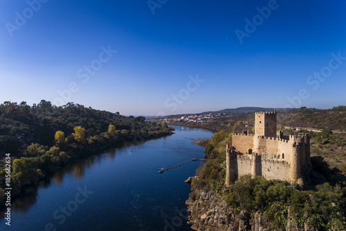 Aerial view of the Armourol Castle with a boat passing in the Tagus River in Portugal; Concept for travel in Portugal