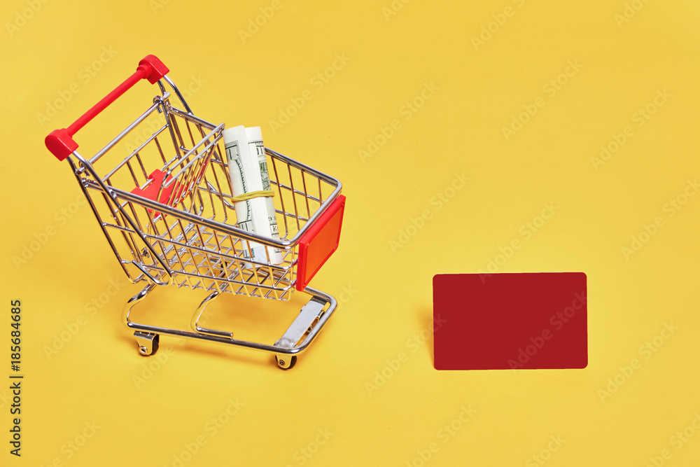 shopping trolley with credit card and dollars on yellow backgroud