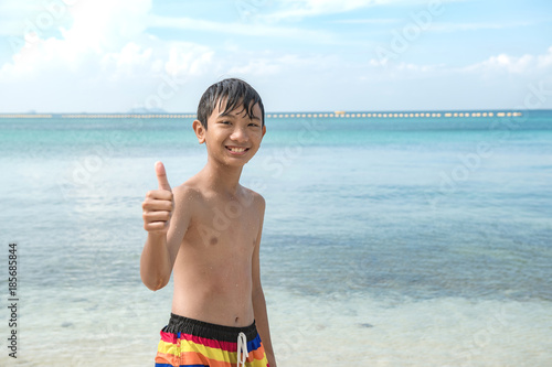 Young chinese boy on beach portrait. Young boy standing in ocean thumb up  at camera. Chinese asian boy, tanned skin. foto de Stock | Adobe Stock