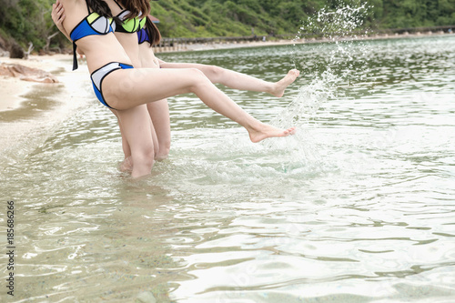 Fototapeta Naklejka Na Ścianę i Meble -  Group of beautiful young single chinese women having fun on beach. Kicking water, wearing bikini, beach hat.