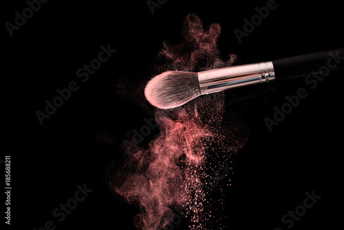 Make up brush with red powder dust explosion cloud, selective focus, close up