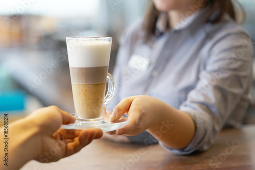 The waitress takes a cup with a coffee cappuccino for the client at the restaurant. The concept of service and maintenance.