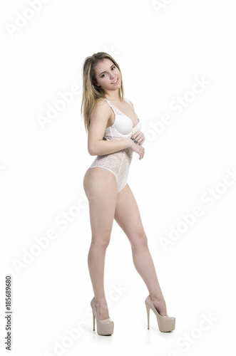 Girl in a white bodysuit and white shoes posing in a Studio.