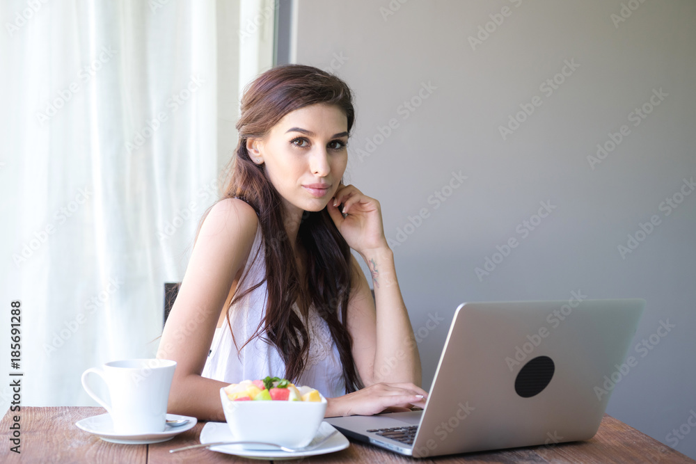 Woman having coffee and working outside. Working on laptop during her vacation in a tropical hotel. White female with white dress. Agile. modile office concept. Woman having coffee and working outside. Working on laptop during her vacation in a tropical hotel. White female with white dress. Agile. modile office concept.