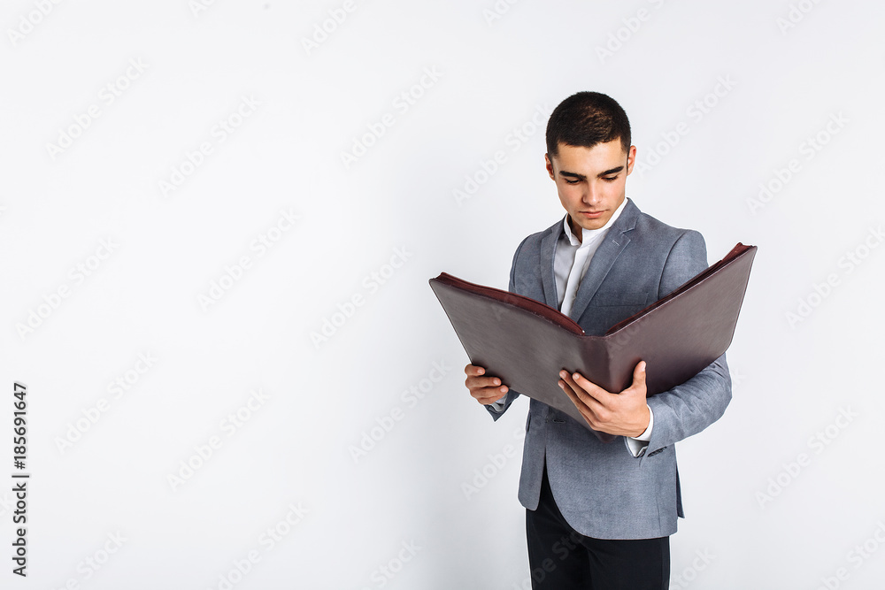 Handsome man with folder man reading a menu, a stylish business guy in suit in Studio on white background Handsome man with folder man reading a menu, a stylish business guy in suit in Studio on white background