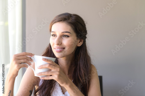 Fototapeta Naklejka Na Ścianę i Meble -  Woman having coffee and smile. Beautiful white woman having her morning coffee and smile looking very happy.