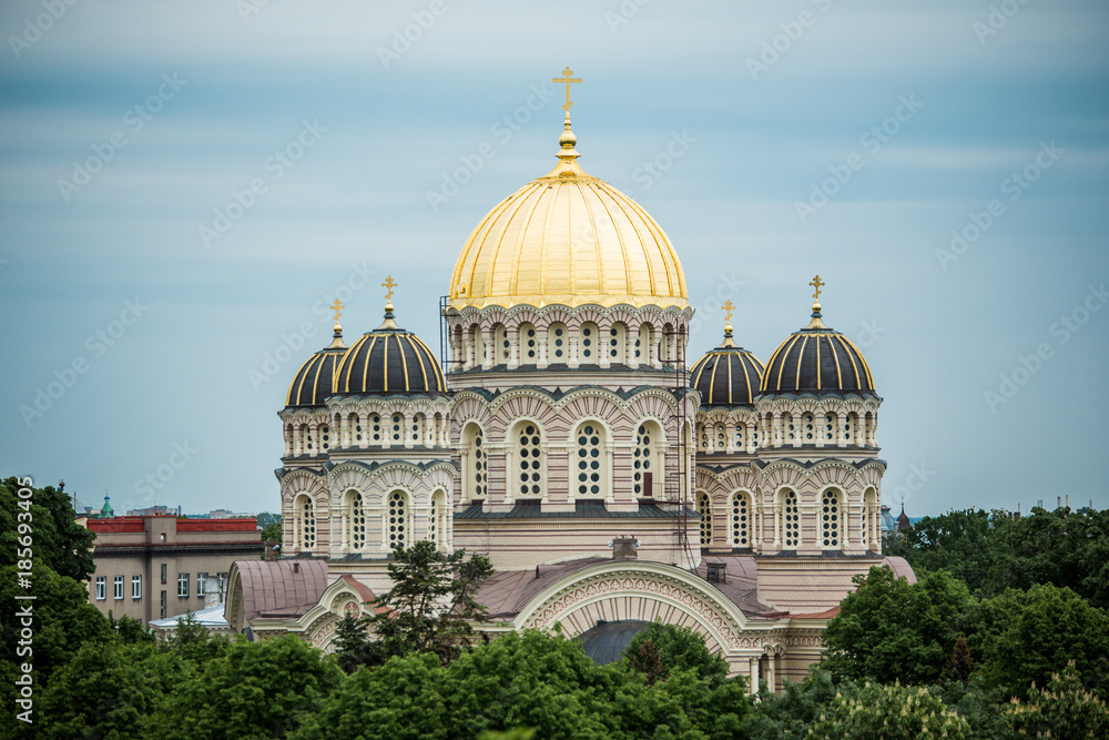 Obraz premium Orthodox Cathedral golden dome above Riga city trees.