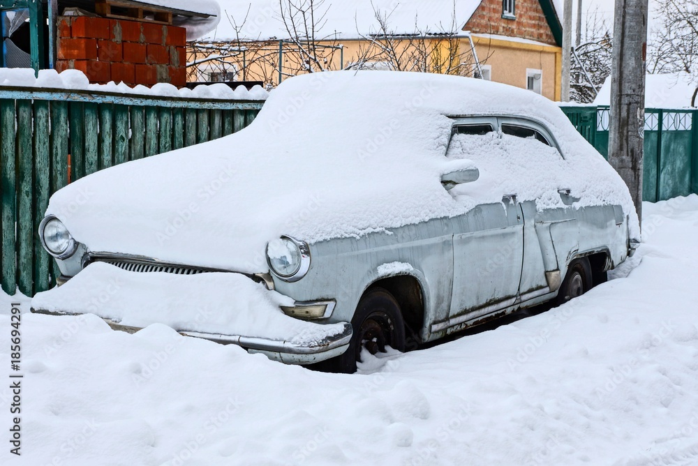 ретро автомобиль серого цвета под снегом стоит на улице
