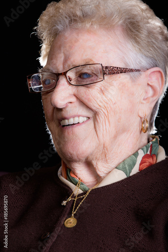 Portrait of a happy senior woman smiling at the camera. Over black background.