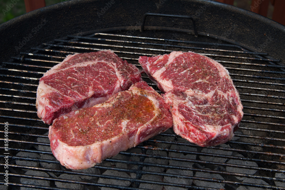Three steaks about to be cooked on a grill Three steaks about to be cooked on a grill