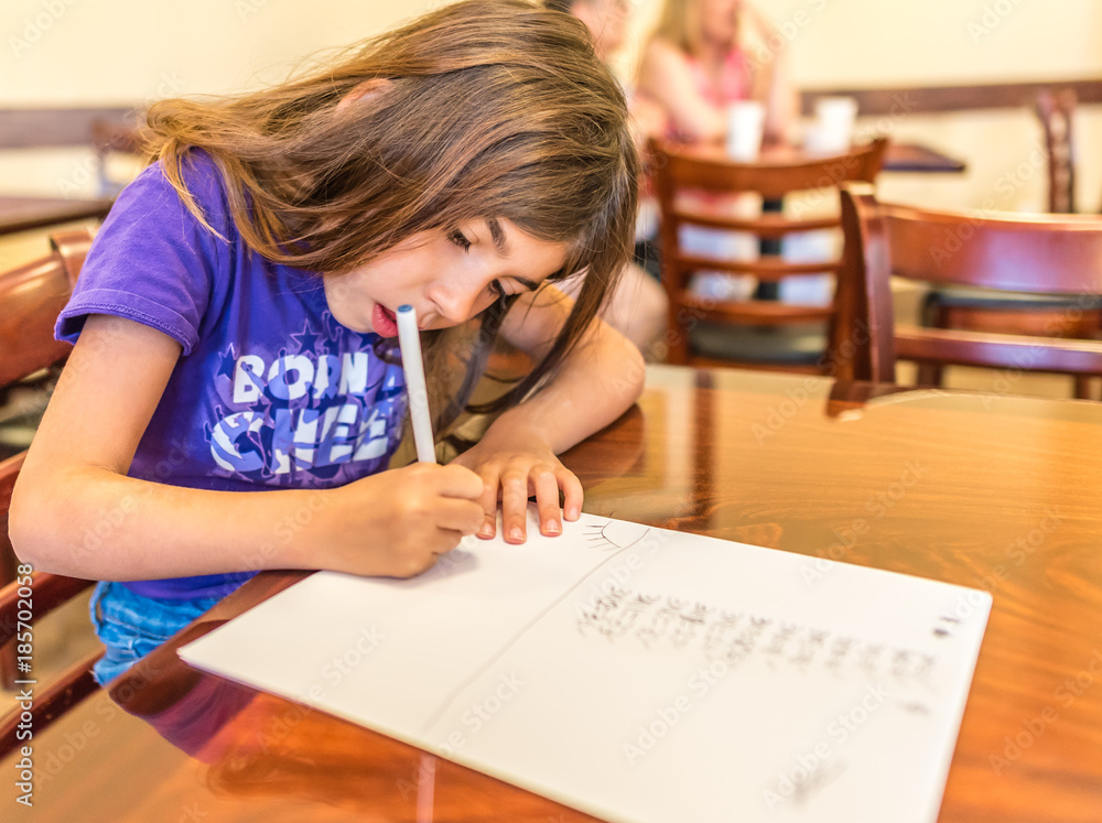Vacationing caucasian girl works on homework in the hotel breakfast area in California Vacationing caucasian girl works on homework in the hotel breakfast area in California