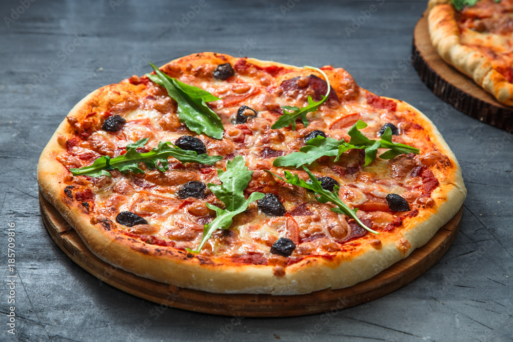 Homemade pizza with tomato, salumi, arugula and olives. Dark background