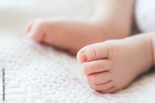 small and cute feet of newborn on the bed. charms of motherhood. new life concept.