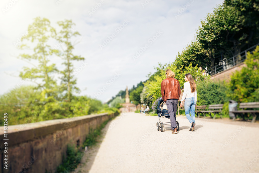 Fototapeta premium Young Parents With Baby Stroller In The Park