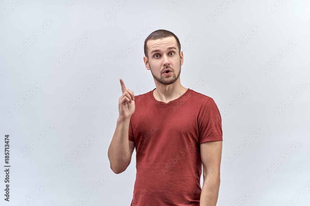 young bold expressive young man lifts a finger upwards with a thoughtful expression and wide open eyes. Concept ideas inspiration problem solution young bold expressive young man lifts a finger upwards with a thoughtful expression and wide open eyes. Concept ideas inspiration problem solution