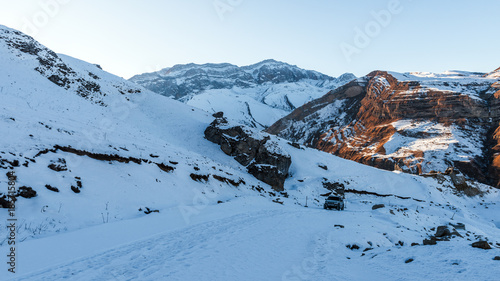 Off-road car rises on the slope of the snow-capped mountain photo