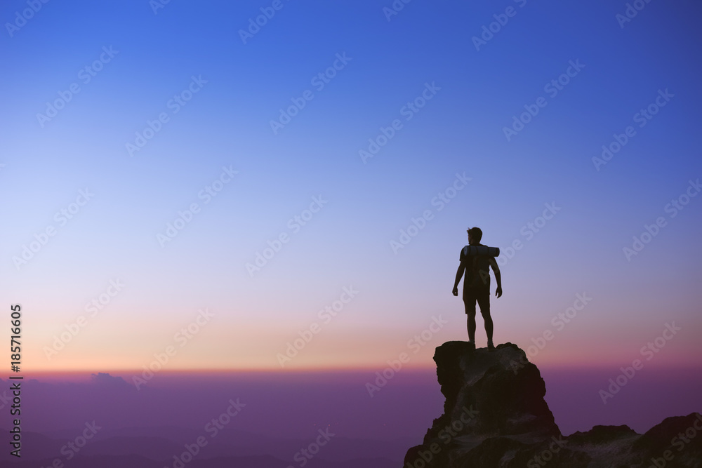 Man's silhouette on background of sunset sky