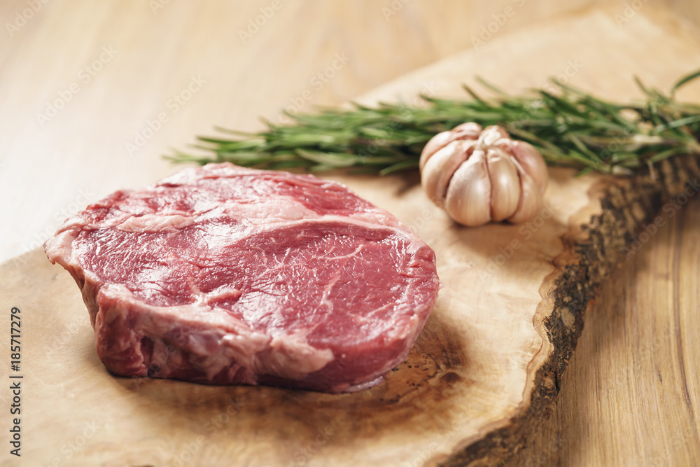 fresh raw rib eye steak on wood board on kitchen table fresh raw rib eye steak on wood board on kitchen table