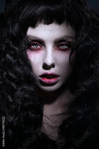 Fototapeta Naklejka Na Ścianę i Meble -  Dark portrait of woman with curly black hair and damaged lips
