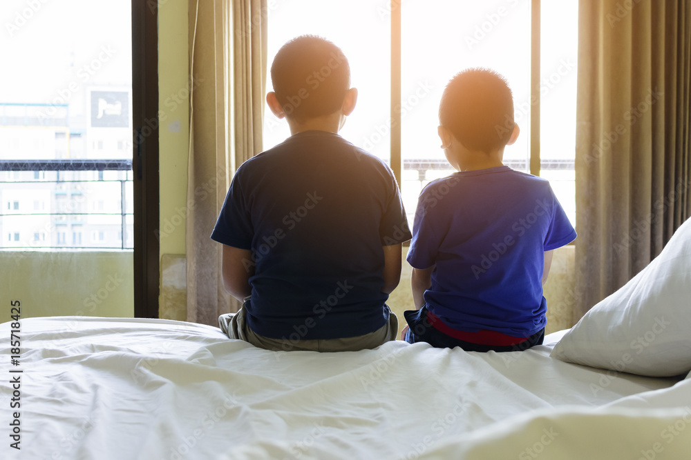 Brother and brother are sitting and looking sunset on the bed in the bedroom Brother and brother are sitting and looking sunset on the bed in the bedroom