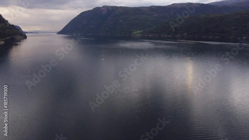 Norwegian fjord, beautiful seascape. Magnificent blue sea with fishing boats. High mountains covered with green trees, in the background sky in cloudy weather. Beautiful view of nature Norway, Europe.