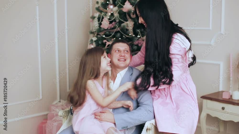 happy family sitting by a Christmas tree happy family sitting by a Christmas tree