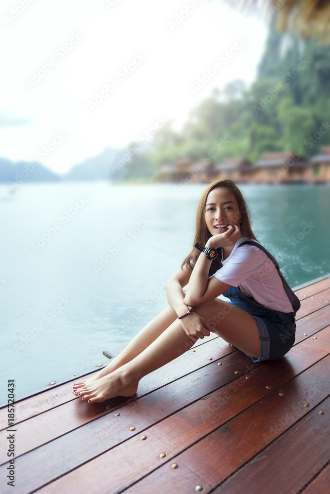 asian beautiful girl sit a relaxing in the lake a rainy season with sunrise light