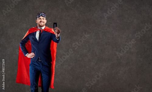A funny man in a superhero costume keeps a credit card in place for text.